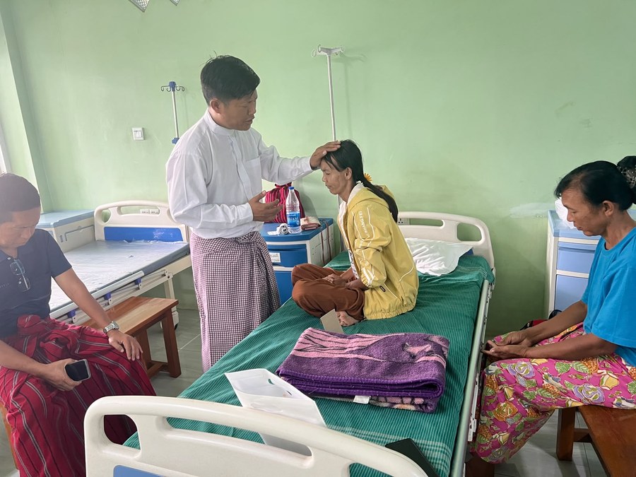 Praying with a family during a home visit in Myanmar